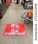 Small photo of Lancaster Ohio/USA-April 2020: Stand Here decals or stickers on the floor at a store checkout lane to enforce social distancing