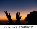 Small photo of Silhouette of man kneeling down praying for worship God at sky background. Christians pray to jesus christ for calmness. In morning people got to a quiet place and prayed. copy space.