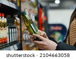 Small photo of Female hand choosing natural olive oil at store. Concept of healthy food, bio, vegetarian, diet.