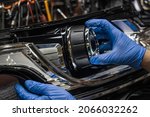 A mechanic wearing rubber gloves installs an LED lens into the headlight housing.Car headlight during repair and cleaning.The mechanic restores the headlight of the car.Restoration of automotive optic