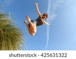 Woman Jumping Off A Sand Dune...