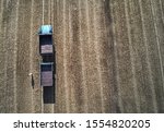 someone have a lot of work at the field. Truck in the field. Aerial shot of an agricultural wheat field, a combine harvester and a truck in Europe. Aerial View Of Rural Landscape. Harvesting Of Wheat 