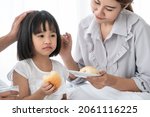 Small photo of Unhappy Asian little girl feeling sick lethargic don't want to eat. young mother take care of her cute daughter and feeds the children breakfast in warm bedroom. happy family On vacation - concept