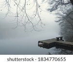 Small photo of Foggy lake landscape with landing stage for boat. Lake, water and tree in the fog. Mystic trees under milky sky in the winter. Silent ambience. Germany, Brandenburg.
