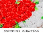 Small photo of Heart of red artificial roses opposite white inanimate background flowers.