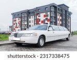 White limousine luxury long car for celebrations and celebrations against the backdrop of a modern city building.