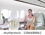Attractive woman sitting and holding champagne glass in private jet