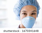 Young female nurse at camera wearing surgical mask and scrubs