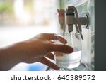 Male hand serving water of a water cooler in plastic cup.
