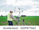Engineer using tablet computer collect data with meteorological instrument to measure the wind speed, temperature and humidity and solar cell system on corn field background, Smart agriculture concept
