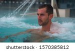Small photo of Portrait of an young man is enjoying and having relax in a whirlpool bath tube in a luxury wellness center.