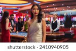Small photo of Advertising Campaign Portrait of a Sophisticated Asian Woman in a Stunning Dress Posing and Looking at Camera in a Glamorous Casino with Hustlers and Gamblers Playing Roulette in Vibrant Background