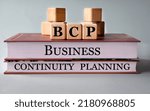 Small photo of BCP (Business Continuity Planning) - acronym on wooden cubes on the background of recumbent books. Business concept