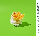 Small photo of French fries in paper bag on green background. Fast food appetizer - fries potato in minimal style. Contemporary fast food menu. Junk food concept. French fries on color table