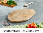 Small photo of Food mockup. Empty wooden board on concrete table with cooking ingredients. Wooden board with spices, greens and tomatoes for menu. Food menu mockup. Cooking composition with empty place