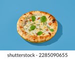 Small photo of Four cheese pizza with tomatoes and spinach on a bright blue background. Minimalist style, side view. Perfect for a modern food photography, takeout or casual meal.