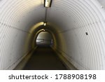Urban pedestrian subway, underpass or walk-through in the shape of white tunnel with ceiling, overhead lamps.