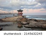 Small photo of Sokcho-si, Gangwon-do, South Korea - October 22, 2021: Sunset view of Yeonggeumjeong Pavilion on rocks at lowt tide against sea horizon in the background