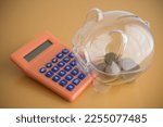 Very little money coins in clear piggy bank and calculator. No planning or knowledge for money management and investment, poverty or bankruptcy concept.