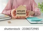 Small photo of Affiliate Program text on a miniature of a wooden house in the hands of a woman at the office table