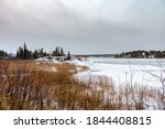 Landscape of Frame lake Yellowknife as the water is freezing with grass and snow in the foreground 