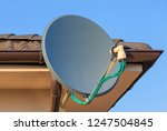 Domestic satellite tv installation under the eaves of home with octo monoblock converter. Residential TV receiver satellite dish with low-noise block downconverter (LNB). Satellite dish antenna.
