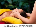 adult woman receives a face and head massage from a private massage therapist