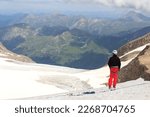 Mountaineer standing on glacier and looking towards Grossglockner High Alpine Road and mountain panorama in Glockner Group, Austria