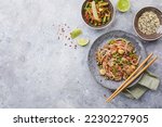 Wok with turkey meat, soba noodles, corn, green peas, green beans and carrots served on gray background with chopsticks. Asian food, concept of street food. Top view with copy space