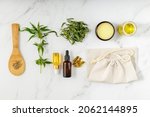 Small photo of Cannabis products. Cannabis medical healing balm salve, CBD and food oil bottles, capsules, tea leaves, sativa seeds on spoon and fabric bag. Top view composition with hemp plant on marble background