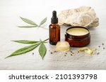 Small photo of Hemp salve balm and relaxing CBD serum oil as a complex in the homeopathy treatment of the musculoskeletal or calming nervous system or psoriasis with cannabis leaves and seeds on stone background