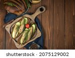 Small photo of Sandwiches with smoked sprats on a wooden server and black background . Sprat sandwich with copy space .