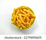 Crunchy cheese flavored puffed corn snacks in a green bowl isolated on white background