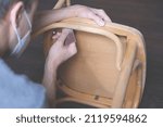 Small photo of Updating furniture, man with respirator sanding a chair close-up