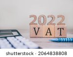 Small photo of VAT 2022 on wooden cubes, calculator and a pen on a wooden table. VAT 2022 - phrase from wooden blocks with letters, VAT 2022 concept