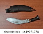 Small photo of Old original nepalese kukri knife used by the gurkha warriors with a huge steel recurved blade, buffalo horn handle and leather sheath