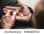 Many multi-colored pills in a Senior's hands. Painful old age. Caring for the health of the elderly