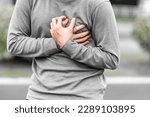 Small photo of Man covering his heart or chest outdoors, concept of heart attack.