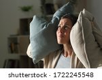 Annoyed adult woman suffering neighbour noise in the livingroom at night at home