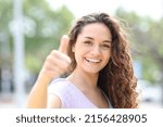 Small photo of Front vie wportrait of a happy woman gesturing thumbs up smiling in a park
