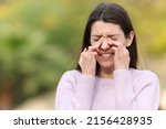 Small photo of Teen scratching itchy eyes complaining outdoors in a park
