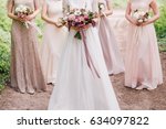 Bride and bridesmaid are holding bouquets of flowers in hands. Bridesmaid are on background. Wedding. Details.
