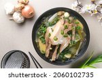 Small photo of Ayam Kuah Jahe or Samgyetang or Ginseng Chicken Soup, traditional Korean chicken soup with ginseng, ginger, garlic and leek served on black bowl. Top view or flatlay.