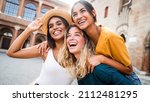 Small photo of Three young multiracial women having fun on city street outdoors - Mixed race female friends enjoying a holiday day out together - Happy lifestyle, youth and young females concept