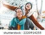 Multiracial couple in love wearing winter clothes celebrating Christmas holiday - Husband and wife having fun hanging out together walking on city street - Winter holidays and relationship concept