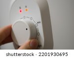 Setting the temperature controller of the heater in the eco mode of operation. Thermostat of a modern heater. A person turns the wheel of the temperature controller with his hand. Selective focus