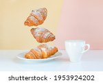 Flying croissants for breakfast and a cup of coffee on a beige background color sunrise. Levitating food, time to wake up call. Modern breakfast still life concept food.