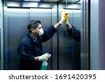 Small photo of coronavirus. cleaning staff disinfecting elevator to avoid contagion