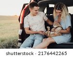 Young Woman and Man Sitting in Trunk of Car with Pet, Happy Couple with Their Red Cat Enjoying Road Trip