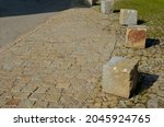 coarse granite stone cube barriers as protection of nice lawn cubes. paved sidewalk platform of the tram protected from cars. paving filled with gaps of grass, quarry product